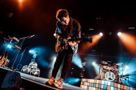 The Wombats guitarist performing under stage lights